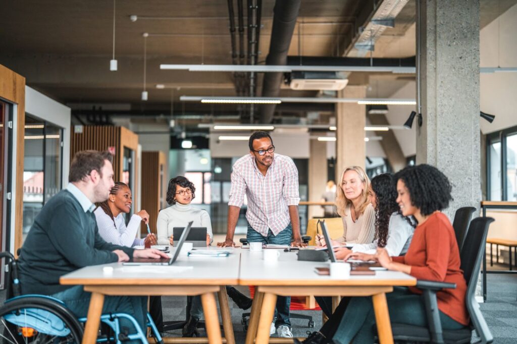 It's important for teams to establish a community of practice around generative AI for marketing. In this image, a marketing team is meeting to discuss strategy. 